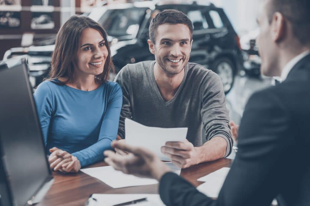 Finance manager talking to couple in dealer showroom