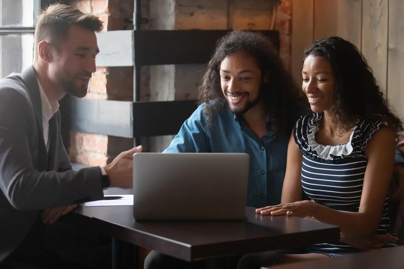 Sales manager and couple looking over finance details on laptop